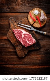 Beef Shoulder Steak On A Wooden Table With Garlic And Red Pepper