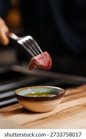 Beef steak bite on a fork dipped into sauce
Close up of seared beef being dipped in gravy
Juicy beef steak piece served with dipping sauce