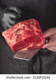 Beef steak in chef hands with knife on black background