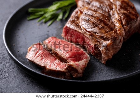 Beef Steak medium rare on a black plate. Grey background. Close up. 