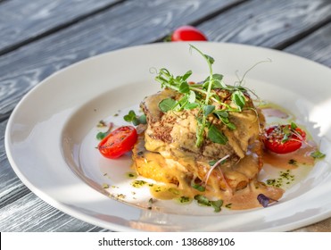 Beef Steak On Golden Crispy Potatoes With Cheese And Tomatoes, Garnished With Microgreen On The Table On A Sunny Day