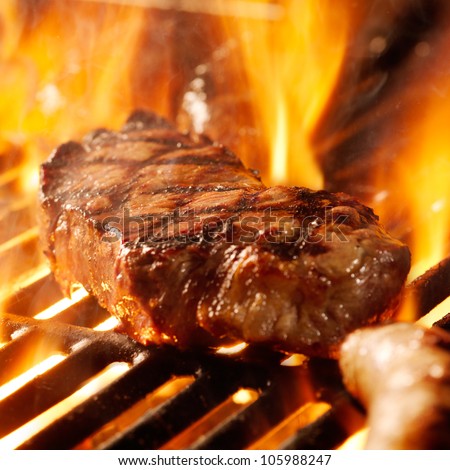 beef steak on the grill with flames.