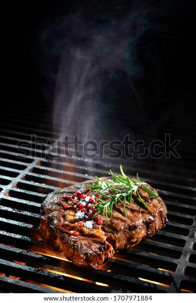 Beef steak on
the grill with smoke and
flames