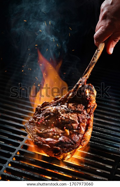 Beef steak on\
the grill with smoke and\
flames