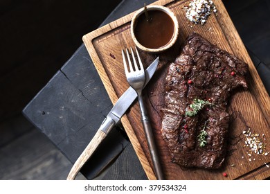 Beef steak. Piece of  Grilled BBQ beef marinated in spices and herbs on a rustic wooden board over rough wooden desk with a copy space. Top view