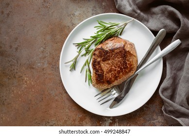 Beef Steak With Rosemary Served In A White Plate, View From Above