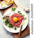 Beef steak tartare on light background. French cuisine concept. Top view, flat lay, copy space