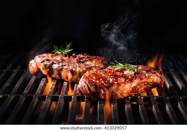 Beef steaks on the grill\
with flames