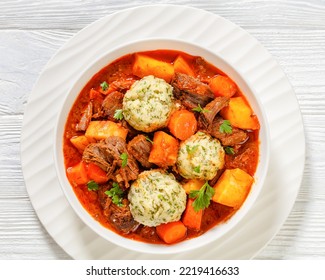 Beef Stew With Dumplings And Vegetables In Rich Tomato And Stock Based Gravy In White Bowl, British Cuisine, Horizontal View From Above, Flat Lay, Close-up