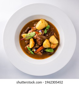 Beef Stew With Potatoes, Irish Stew Or Guinness Stew Made In A Crockpot Or Slow Cooker, Delicious Stew Estofado With Beef And Vegetables Top View, Flat Lay On A White Background