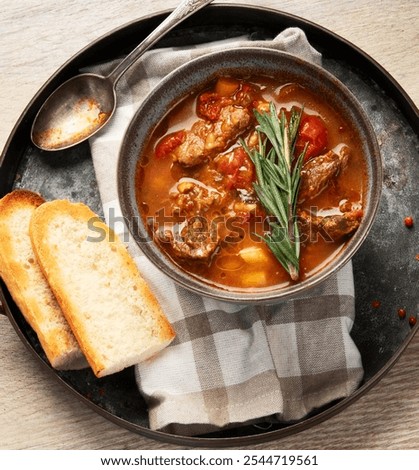Beef Strips Bourgeon with Carrots and Small Onions in grey Bowl on a wooden background. Top view. Copy space.