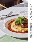 Beef stroganoff with mashed potatoes and herbs in sauce in a plate on the table