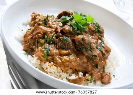 Beef stroganoff over white rice, garnished with parsley.
