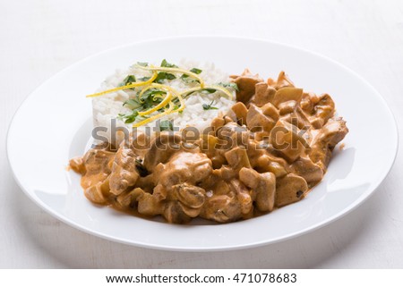 beef stroganoff with rice on white plate
