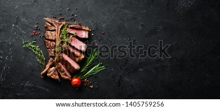 Beef T-Bone steak on a black table. Top view. Free space for text.