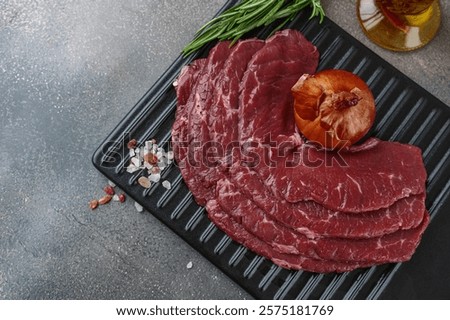 Beef, thin slices of beef bacon on a cutting board with onions and salt for marinade. Top view. Copy space