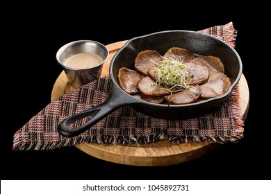 Beef tongue in cast iron skillet on a dark background