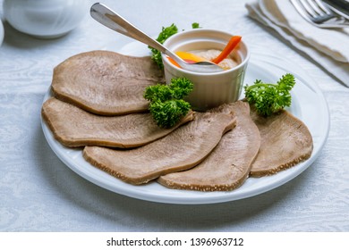 Beef tongue with horseradish on white plate 