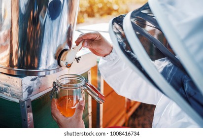 Beekeeper Filling Up A Honey Jar