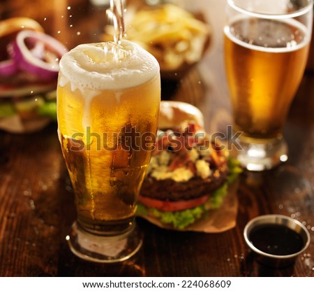 beer being poured into glass with gourmet hamburgers