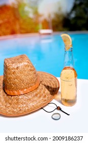 Beer bottle with lemon slice at the poolside. Summer cool refreshment by the blue water. Vertical photo. Copy space