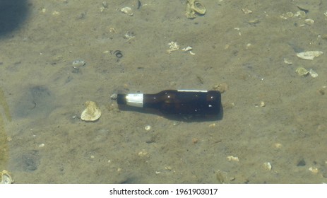 Beer Bottle On Ocean Floor Through Clear Water Up Close