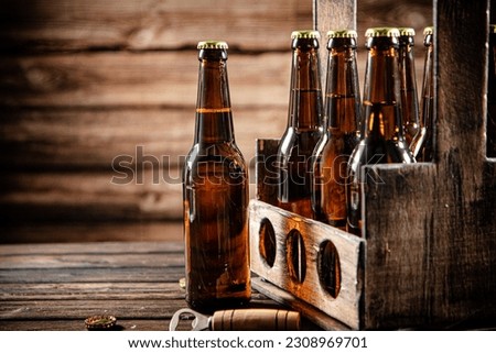 Beer bottles in an old box. On wooden background.