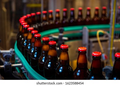 Beer bottles on the conveyor belt in the beer factory / with red caps (high ISO image) - Powered by Shutterstock