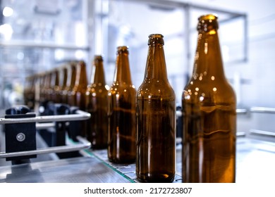 Beer Bottles On Production Line Being Filled With Alcohol In Beverage Factory.