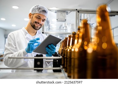 Beer bottling plant and factory worker controlling alcohol beverage production before distribution. - Powered by Shutterstock