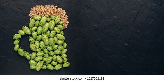 Beer Concept. Natural Ingredients Of Brewery Process- Green Hops Cones Pattern And Wheat Grains In Form Of Shape Of Beer Pint. Oktoberfest Idea Board With Copy Space On Black Background.