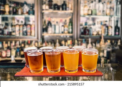 Beer Flight Of Eight Sampling Glasses Of Craft Beer On A Serving Board In A Bar.