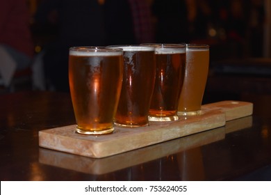 Beer flights samples served on a plank in chilled glasses in a rustic brewery. - Powered by Shutterstock