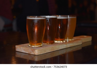 Beer flights samples served on a plank in chilled glasses in a rustic brewery. - Powered by Shutterstock