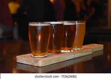 Beer flights samples served on a plank in chilled glasses in a rustic brewery. - Powered by Shutterstock