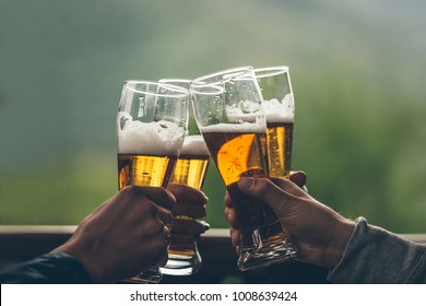 Beer with foam light tall boys in the hands of friends raising a toast closeup - Powered by Shutterstock