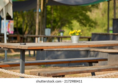 Beer Garden With Flowers Decoration On Table. Seating In The Sun With Plant In Tin Bucket.