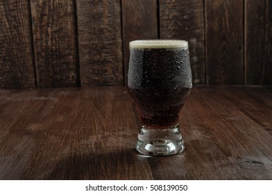 Beer Glass With Drops On Dark Wood Table. Wood Texture