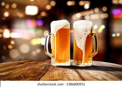 Beer in glass and free space for your bottle. Wooden table and dark interior of bar. 