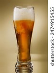 Beer. Glass of fresh and cold beer with drops. Pouring craft golden beer on a golden background.  Shallow depth of field
