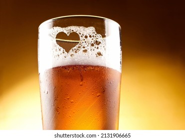 Beer Glass with a heart of foam with a yellow background 
