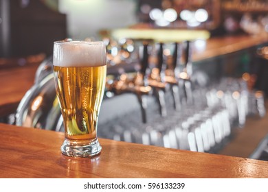 Beer Glass On A Bar Table. Beer Tap On Background