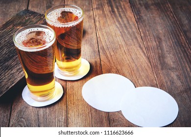 Beer In Glass On Wooden Bar And Blank White Paper For Beer Coasters.