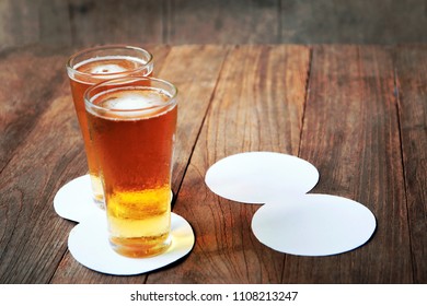 beer in glass on wooden table and blank white paper for coasters. - Shutterstock ID 1108213247