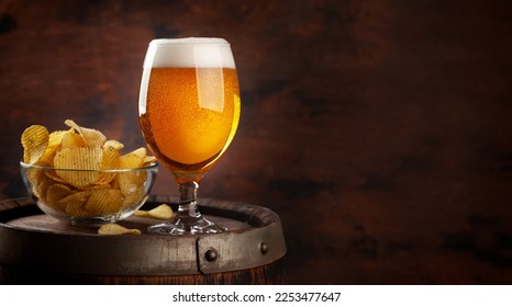 Beer glass and potato chips on wooden barrel. With copy space - Powered by Shutterstock