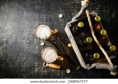 Beer in glasses with an old crate of bottles. On rustic background.