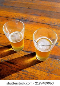 Beer Glasses On The Rustic Wooden Table Under Sunlight.