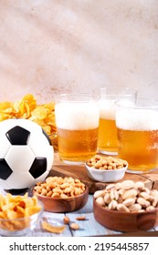 Beer In Glasses And Snack On Wooden Table With Football Ball, Football Game Night Food. Snack And Drink For Watching Football Games And Championships