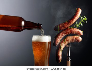 Beer and grilled Bavarian sausages with rosemary. Sausages on a fork sprinkled with rosemary. Copy space.