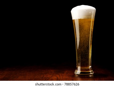 Beer Into Glass On A Black And Wooden Table